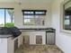 Inviting outdoor kitchen featuring a built-in grill, mini fridge, sink, and stylish brick flooring at 12198 Se 176Th Loop, Summerfield, FL 34491