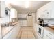 Functional kitchen with white cabinetry, appliances, tile flooring and adjacent laundry area at 1325 Balboa Ct, The Villages, FL 32159