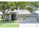 Charming single-story home featuring a three-car garage and lush front yard landscaping with mature tree at 1355 Misty Glen Ln, Clermont, FL 34711