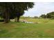 Open green space with mature trees and a tranquil pond, perfect for recreation and relaxation at 1355 Misty Glen Ln, Clermont, FL 34711