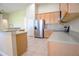 Open-concept kitchen features light wood cabinetry, stainless steel appliances, and tile flooring, offering a modern cooking space at 1355 Misty Glen Ln, Clermont, FL 34711