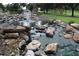 Picturesque water feature with cascading rocks and lush landscaping in a serene setting at 1355 Misty Glen Ln, Clermont, FL 34711