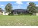 The backyard features a lush lawn and mature landscaping surrounding a screened-in pool area at 1426 Lakemist Ln, Clermont, FL 34711