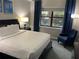 Inviting bedroom featuring a queen-size bed, blue armchair, and a view of the landscaping at 14501 Grove Resort Ave # 3406, Winter Garden, FL 34787