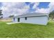 Rear view of a home with a concrete patio and spacious, well-maintained lawn at 14611 Se 95Th Ct, Summerfield, FL 34491