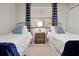 Bright bedroom with twin beds, side table with lamp, and a window with stylish blue patterned curtains at 16300 County Road 455 # 202, Montverde, FL 34756
