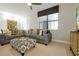 Comfortable living room featuring a gray sectional sofa, patterned ottoman, and a window with blinds at 16300 County Road 455 # 202, Montverde, FL 34756