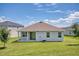 A pristine backyard featuring lush green lawn, a covered patio, and a home with neutral stucco and complementary roof at 1696 Wilson Prairie Cir, Groveland, FL 34736
