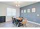 Bright dining room featuring a modern chandelier, wood table, and gray accent wall with stylish artwork at 1696 Wilson Prairie Cir, Groveland, FL 34736