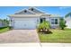 Charming single-story home with a brick driveway, two-car garage, and well-manicured lawn under a blue sky at 1696 Wilson Prairie Cir, Groveland, FL 34736