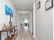 Inviting hallway with wood flooring, decorative wall art, and a console table, leading into a light-filled living area at 1696 Wilson Prairie Cir, Groveland, FL 34736