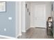 Hallway featuring wood-look flooring, neutral wall paint, and stylish decor leading to the front door at 1696 Wilson Prairie Cir, Groveland, FL 34736