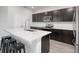 Open kitchen with counter seating, featuring stainless steel appliances, dark cabinetry, and quartz countertops with wood floors at 1696 Wilson Prairie Cir, Groveland, FL 34736