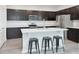 Well-lit kitchen featuring a quartz countertop island with barstool seating, dark cabinets, and stainless steel appliances at 1696 Wilson Prairie Cir, Groveland, FL 34736
