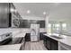 Modern kitchen featuring stainless steel appliances, dark cabinetry, and a quartz countertop island, with wood flooring at 1696 Wilson Prairie Cir, Groveland, FL 34736