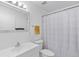 Bright bathroom features a single vanity sink, mirror, and a shower with a striped curtain at 1726 Tropical Ct, Tavares, FL 32778