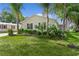 Home featuring a well-manicured lawn, complemented by lush landscaping and mature palm trees at 1815 Kaufman Cir, Lady Lake, FL 32159