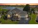 Beautifully landscaped home with a grey roof and a stunning lake view at sunset at 1920 Iglesia St, The Villages, FL 32159