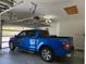 Spacious two-car garage with epoxy flooring features overhead storage, an automatic door, and a blue truck at 1920 Iglesia St, The Villages, FL 32159