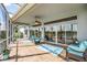 Covered patio showcasing stone floors, ceiling fan, and sliding glass doors with a lake view at 1920 Iglesia St, The Villages, FL 32159