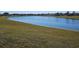 Wide shot of a pond with bright blue, reflective water and thick green grass shoreline at 1920 Iglesia St, The Villages, FL 32159