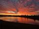 Beautiful view of a pond reflecting a sunset sky with orange and red tones at 1920 Iglesia St, The Villages, FL 32159