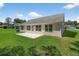 The backyard has a grassy lawn with a concrete patio, mature landscaping, and exterior house views at 206 Palermo Pl, Lady Lake, FL 32159