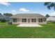 The backyard includes a grassy lawn with a concrete patio, mature landscaping, and exterior house views at 206 Palermo Pl, Lady Lake, FL 32159
