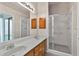 Bathroom with dual sinks, wood cabinets, large mirror and walk-in shower with glass door at 206 Palermo Pl, Lady Lake, FL 32159