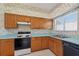 Eat-in kitchen featuring floral wallpaper, wood cabinets, and black appliances at 206 Palermo Pl, Lady Lake, FL 32159
