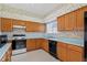 Eat-in kitchen featuring floral wallpaper, wood cabinets and black appliances at 206 Palermo Pl, Lady Lake, FL 32159