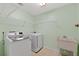 The laundry room offers a newer washer and dryer with a utility sink and wire shelving at 206 Palermo Pl, Lady Lake, FL 32159