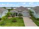 Charming single-story home with a well-manicured lawn, palm trees, and a brick driveway leading to a two-car garage at 2330 Nuthatch St, St Cloud, FL 34771