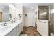 Bathroom features double sinks, wood look floors, framed mirrors, and a tiled glass door shower at 2585 Constance Ct, The Villages, FL 32163