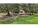 Charming house exterior with a patio and expansive yard, surrounded by mature trees and greenery at 31136 Senese Rd, Sorrento, FL 32776