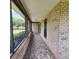 Long enclosed porch with brick floors, offering views of the landscape and greenery at 3147 Rambler Ave, St Cloud, FL 34772