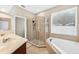 Bright bathroom featuring double sinks, a glass-enclosed shower, and a soaking tub next to a window at 33316 Irongate Dr, Leesburg, FL 34748