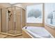 Bathroom featuring a glass shower and corner tub with neutral-toned tile and natural light from two windows at 33316 Irongate Dr, Leesburg, FL 34748