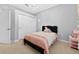 Bright bedroom featuring light grey walls, carpet floors, and a black bed frame with a pink comforter at 33316 Irongate Dr, Leesburg, FL 34748