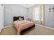 Cozy bedroom featuring light grey walls, carpet floors, and a black bed frame with a pink comforter at 33316 Irongate Dr, Leesburg, FL 34748