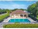 Community pool with covered lounge area with tables and chairs, surrounded by lush landscaping at 33316 Irongate Dr, Leesburg, FL 34748