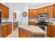 Warm kitchen with wood cabinets, granite countertops, and modern stainless steel appliances at 33316 Irongate Dr, Leesburg, FL 34748
