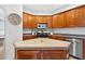 Charming kitchen featuring wooden cabinetry, tiled countertops, and modern stainless steel appliances at 33316 Irongate Dr, Leesburg, FL 34748