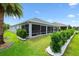 Exterior photo of a well-manicured backyard featuring lush greenery, palm trees and a screened-in patio at 3566 Gentle Ter, The Villages, FL 32163