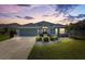 Beautiful home exterior featuring manicured landscaping, neutral paint and elegant architectural details at dusk at 3566 Gentle Ter, The Villages, FL 32163
