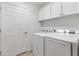 Bright laundry room with white cabinets, a washing machine, and a dryer for convenient laundry tasks at 3566 Gentle Ter, The Villages, FL 32163