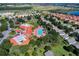 Aerial view of a community with a vibrant swimming pool, tennis courts, lush landscaping, and a clubhouse at 3586 Eversholt St, Clermont, FL 34711