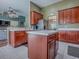 Open-concept kitchen boasts rich wood cabinets, a center island, and stainless steel appliances, seamlessly connecting to the living area at 359 Blue Branch St, Eustis, FL 32736