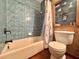 Bathroom features a blue tiled shower/tub with wooden floors, and decorative shelving above toilet at 3664 Se 45Th Pl, Ocala, FL 34480