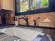 Close-up of the kitchen sink with a black faucet, pull-out sprayer, and black granite counter with decorative tile at 3664 Se 45Th Pl, Ocala, FL 34480